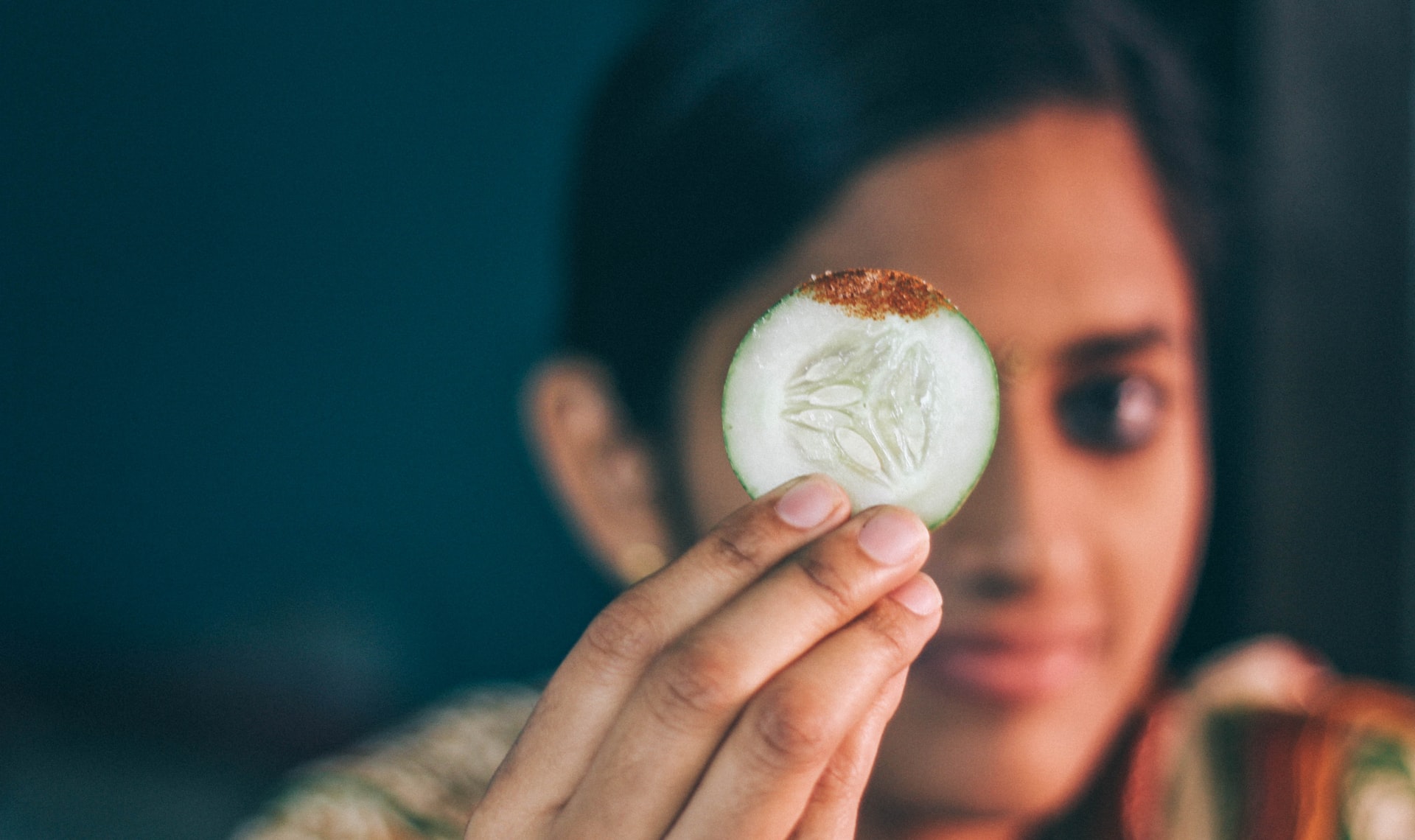 moça segurando uma fatia de pepino