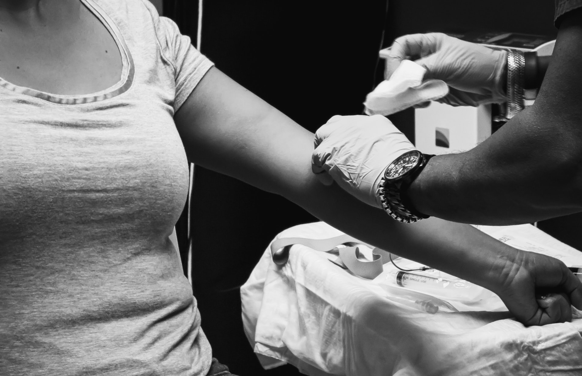 Imagem mostra uma mulher fazendo uma coleta de sangue em um ambiente laboratorial.